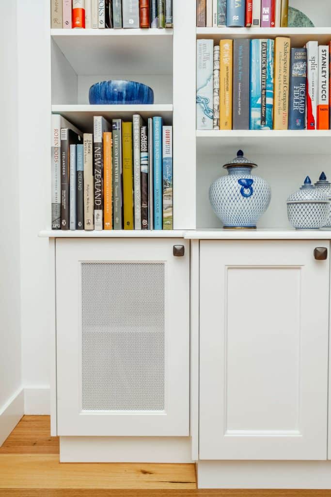 Close-up of a white bookshelf in a New Farm, Brisbane residence, showcasing a variety of books, travel mementos, and blue-and-white ceramic ware, reflecting a personal and curated interior design.